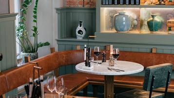 A restaurant interior with a round table, leather seating, and decorative vases on shelves.