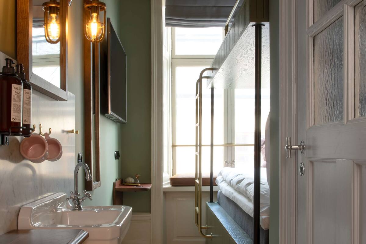 Un baño con lavamanos, espejo e iluminación colgante.