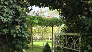A garden pathway leading to a gated area with a hedge on one side and a small tree on the other. - Hotel Ahrbella (Bad Neuenahr-Ahrweiler)