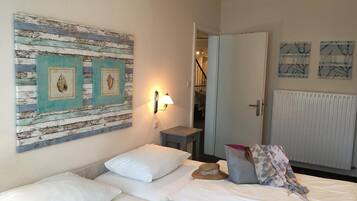 Une chambre d’hôtel comprenant un lit, une table de chevet, une lampe fixée au mur et des œuvres d’art.