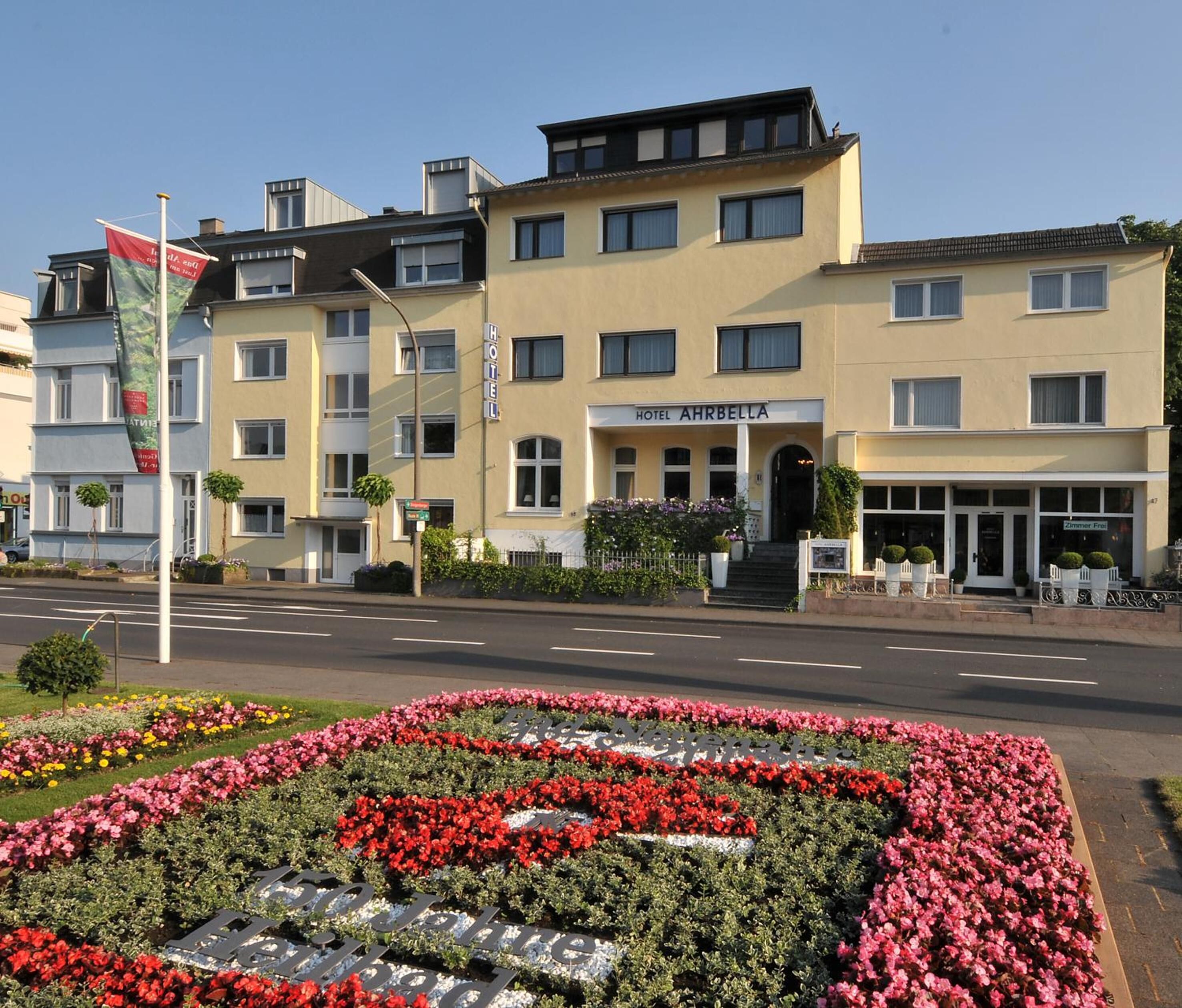 A hotel with a yellow facade, multiple windows, and a sign reading "HOTEL AHRBELLA".