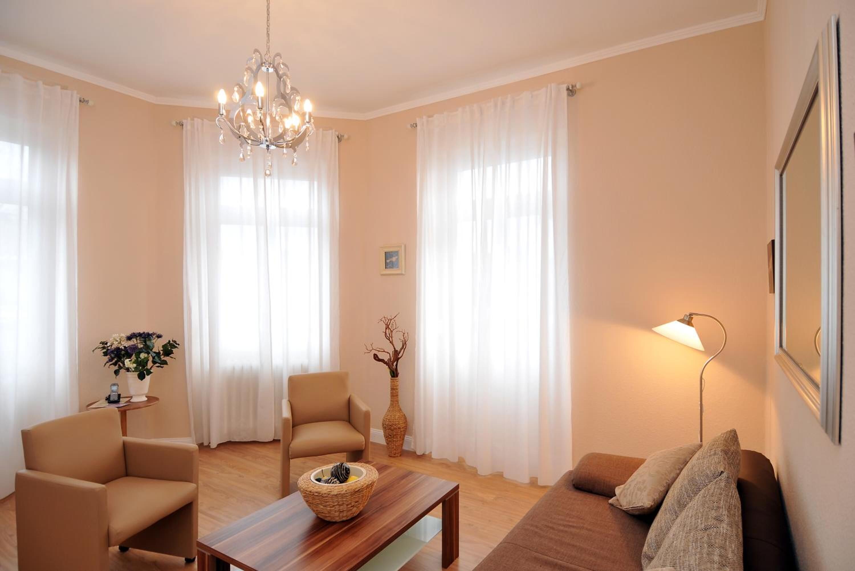 A living room with a chandelier, two armchairs, a sofa, a coffee table, and a lamp.