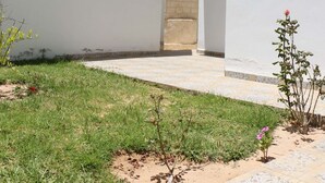 Un bâtiment blanc avec une petite fenêtre et une porte. Un chemin mène à la porte.