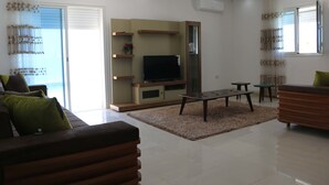 Un salon moderne avec un téléviseur à écran plat, un canapé, une table basse et une table à manger.