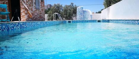 Una piscina al aire libre, sombrillas, sillones reclinables de piscina