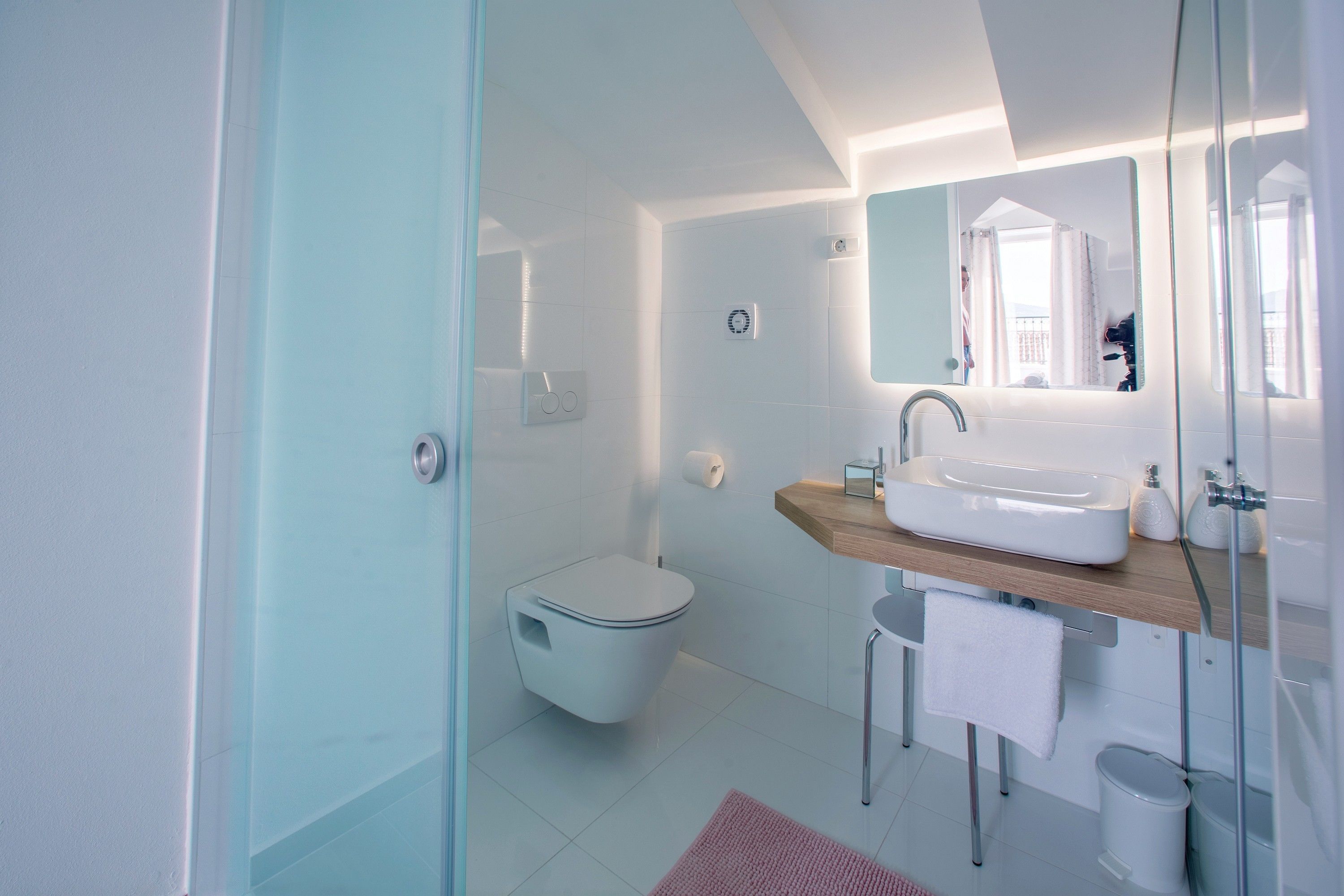 Un baño moderno con inodoro, lavamanos y espejo.