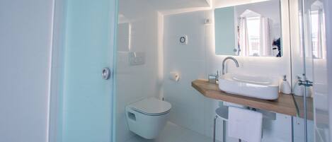 Un baño moderno con inodoro, lavamanos y espejo.