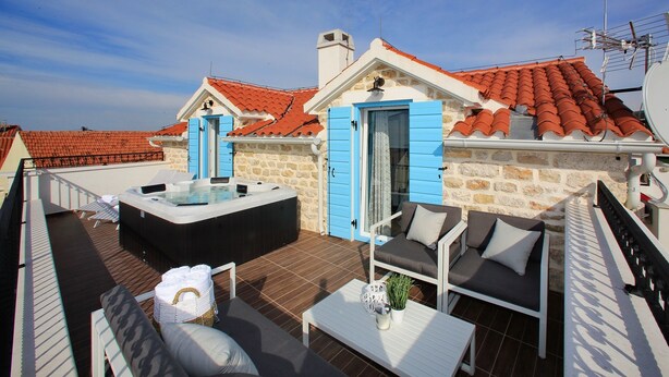 A rooftop terrace with a hot tub, outdoor seating, and a stone wall. - Villa Vito (Bibinje)