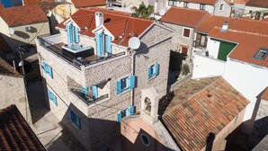 A stone building with red-tiled roofs, blue shutters, and a rooftop pool. - Villa Vito (Bibinje)