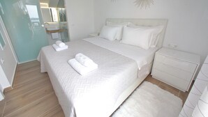 A neatly made bed with white linens and pillows, a white nightstand, and a fluffy white rug. - Villa Vito (Bibinje)