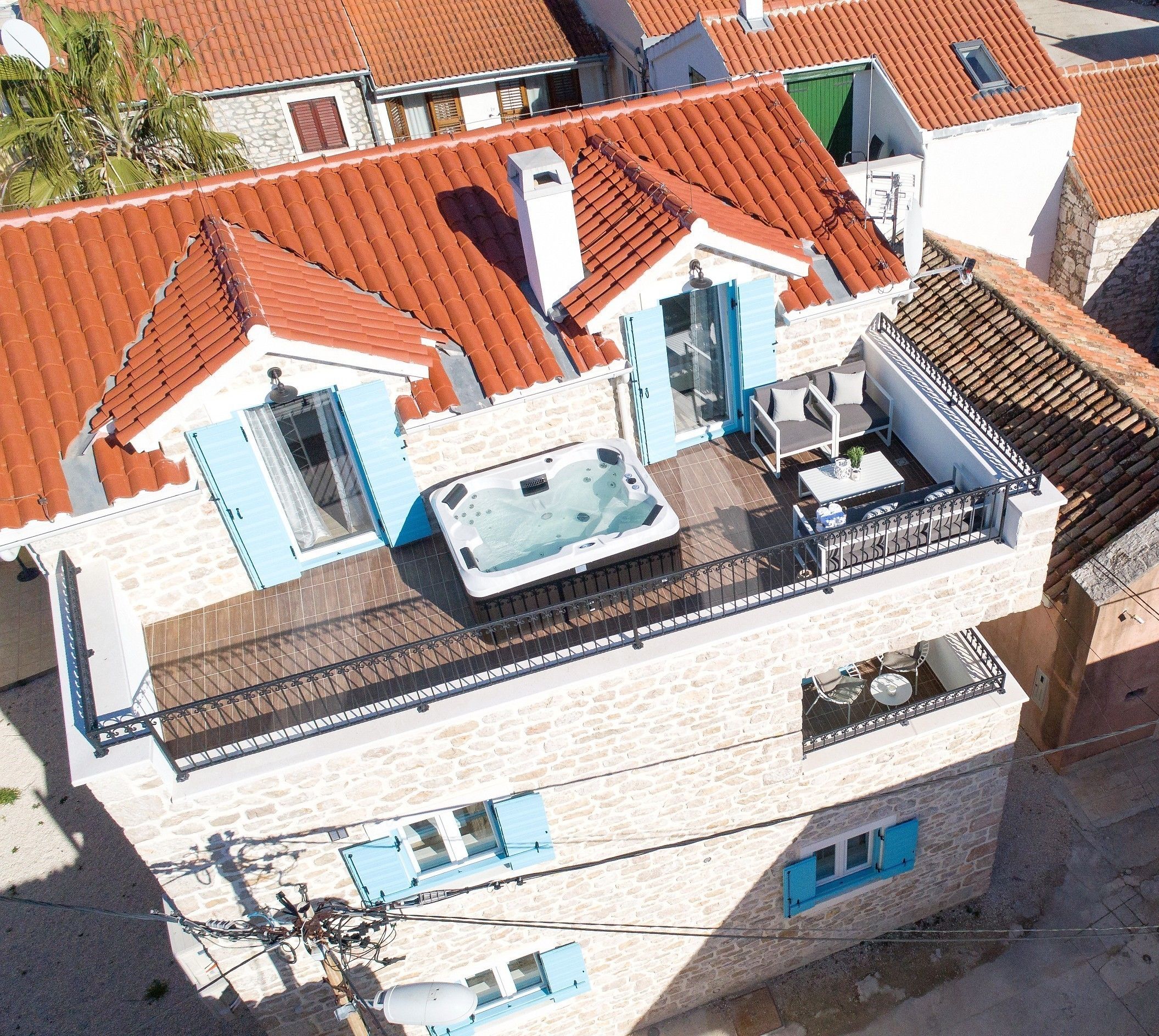 A residential building with a rooftop patio, a hot tub, and a balcony with outdoor furniture.