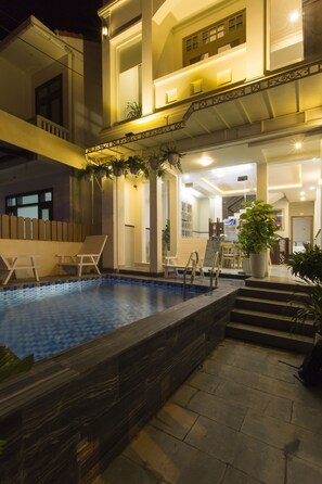 A two-story building with a swimming pool, outdoor seating, and a staircase leading to the upper floor.
