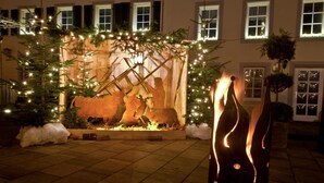 A nativity scene with a stable, surrounded by Christmas lights and decorations, set against a building facade with windows. - Hotel Saarburger Hof (Saarburg)