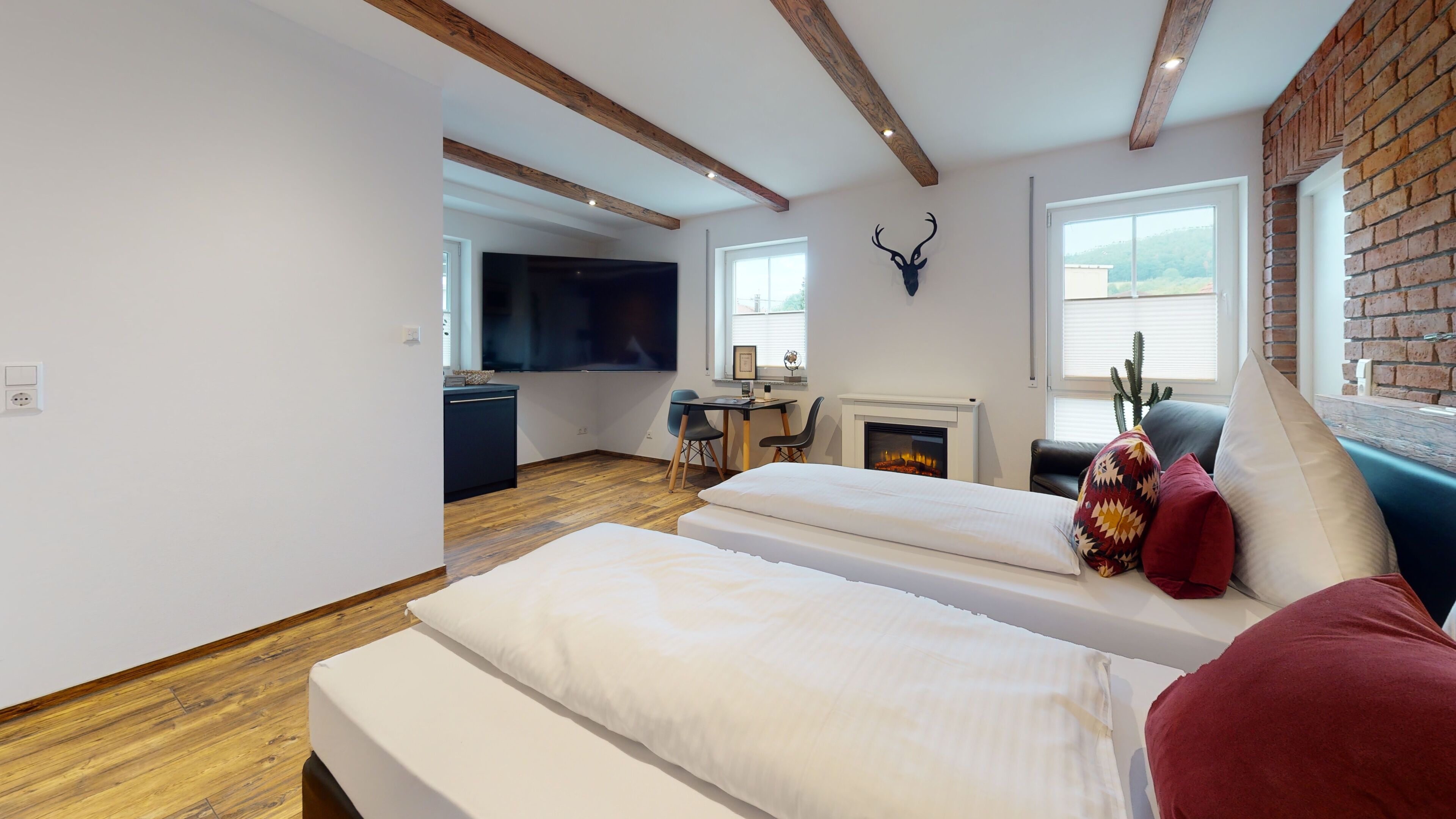 A modern room with a fireplace, a bed, a desk, and a TV.