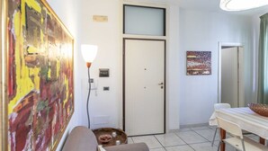 A room with a white door, a painting on the wall, a table with a bowl, and a lamp. - Appartamento White Fronte Mare (Gallipoli)