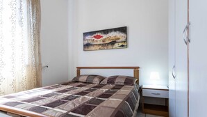 A bedroom with a bed, a nightstand, a lamp, and a painting on the wall. - Appartamento White Fronte Mare (Gallipoli)