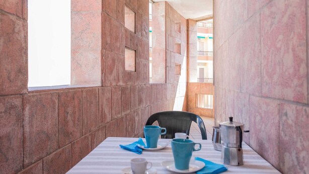 A table set with blue cups and saucers, a coffee pot, and a chair in a room with stone walls and a window. - Appartamento White Fronte Mare (Gallipoli)