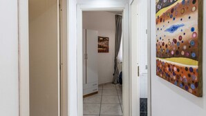 A hallway with a white door, a checkered shower curtain, and a painting on the wall. - Appartamento White Fronte Mare (Gallipoli)