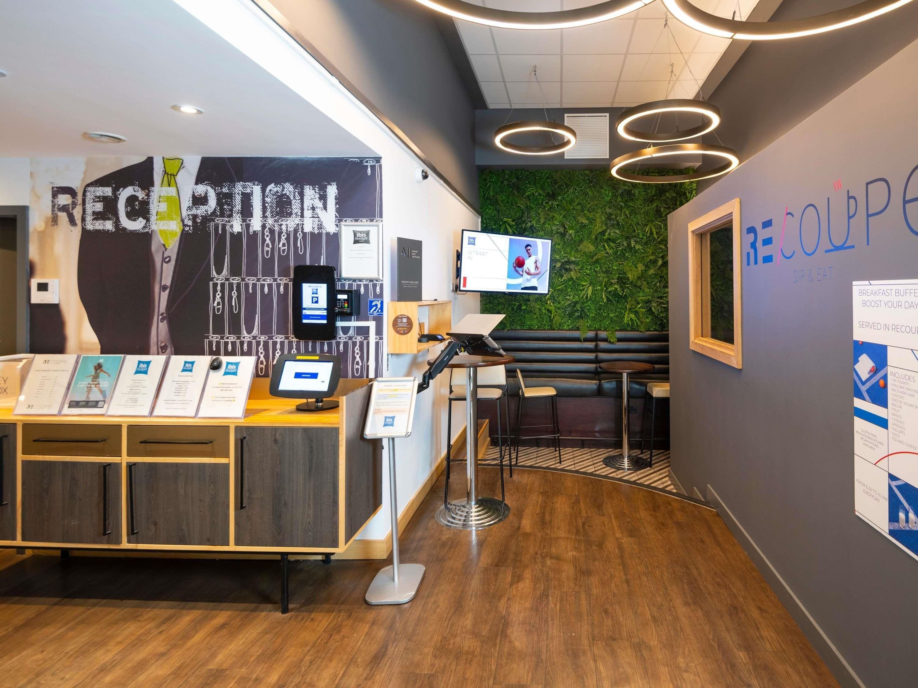 A reception area with a desk, seating, a green wall, and a TV screen.