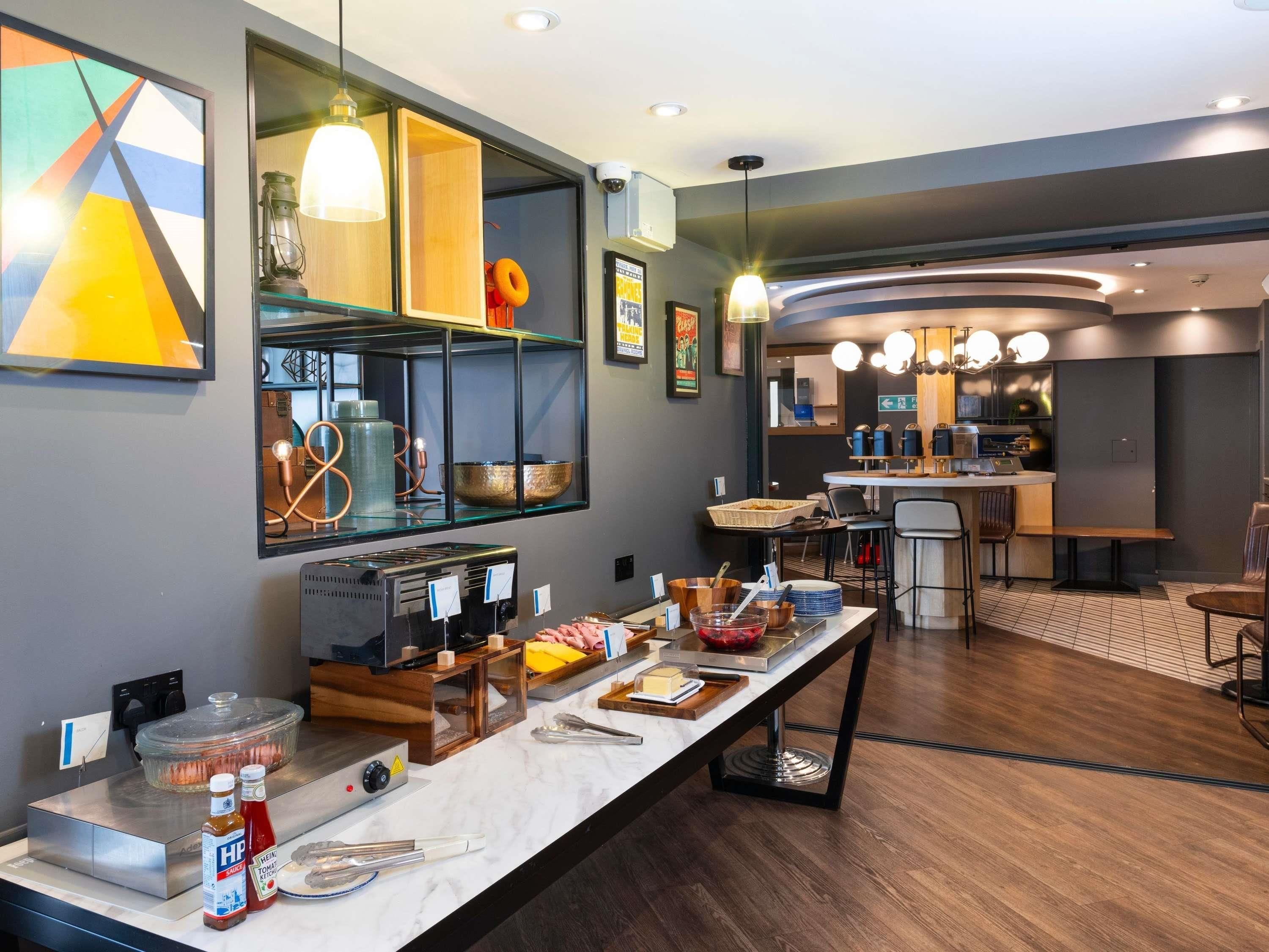 A modern kitchen with a buffet setup, a coffee machine, and a seating area with a bar.