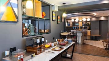 A modern kitchen with a buffet setup, a coffee machine, and a seating area with a bar.