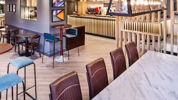 A modern restaurant with a bar area, seating arrangements, and a decorative light fixture.