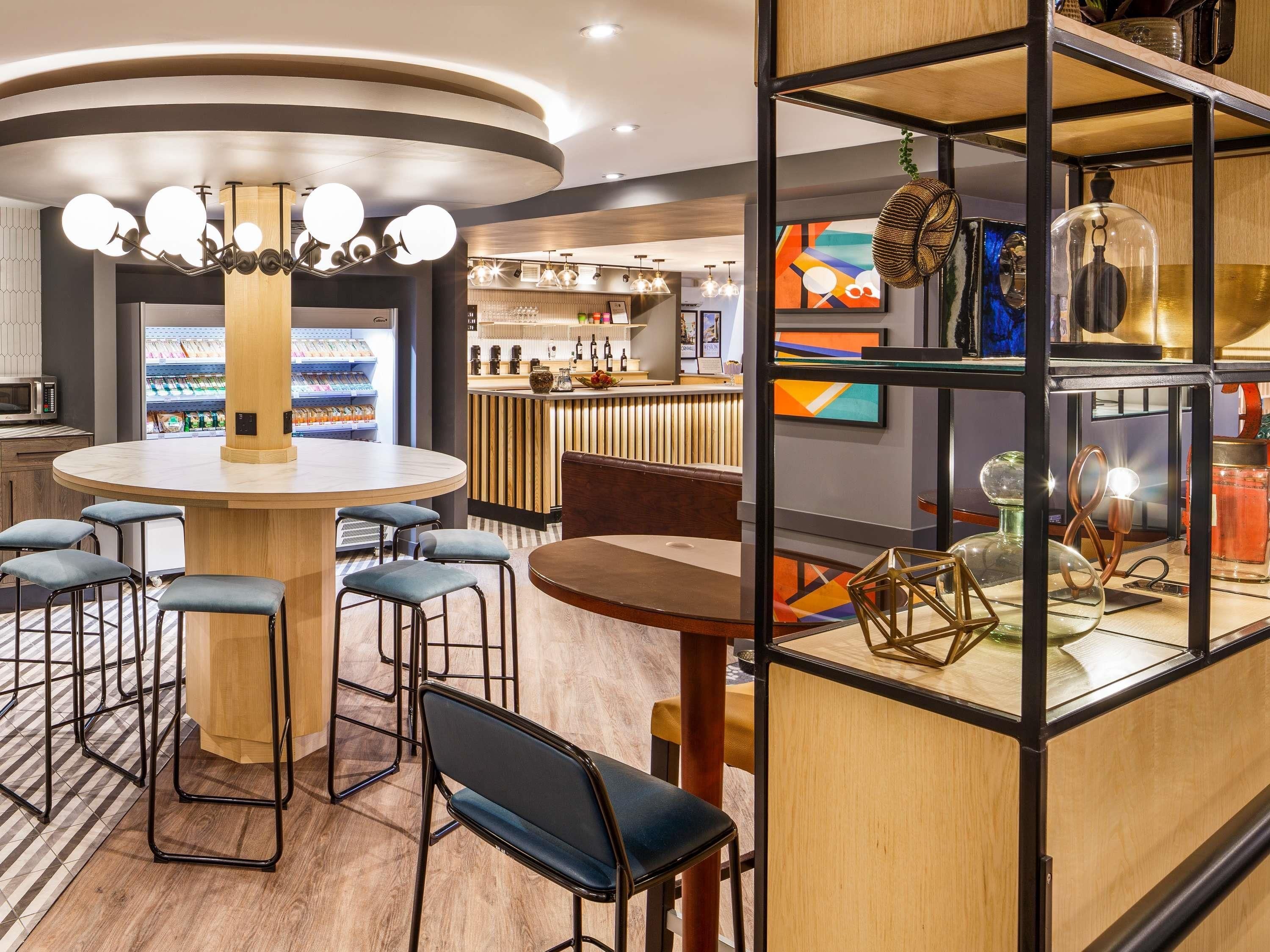 A modern bar area with a round table, bar stools, and a counter.