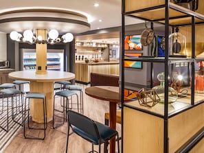 A modern bar area with a round table, bar stools, and a counter. - ibis budget Swindon Town Centre (Swindon)