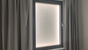 A window with a frosted glass pane and a white frame, surrounded by grey curtains. - ibis budget Swindon Town Centre (Swindon)