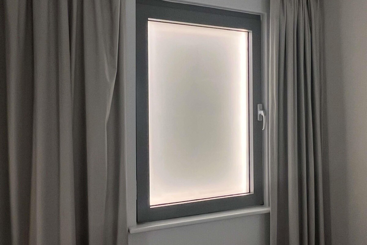 A window with a frosted glass pane and a handle, framed by curtains.