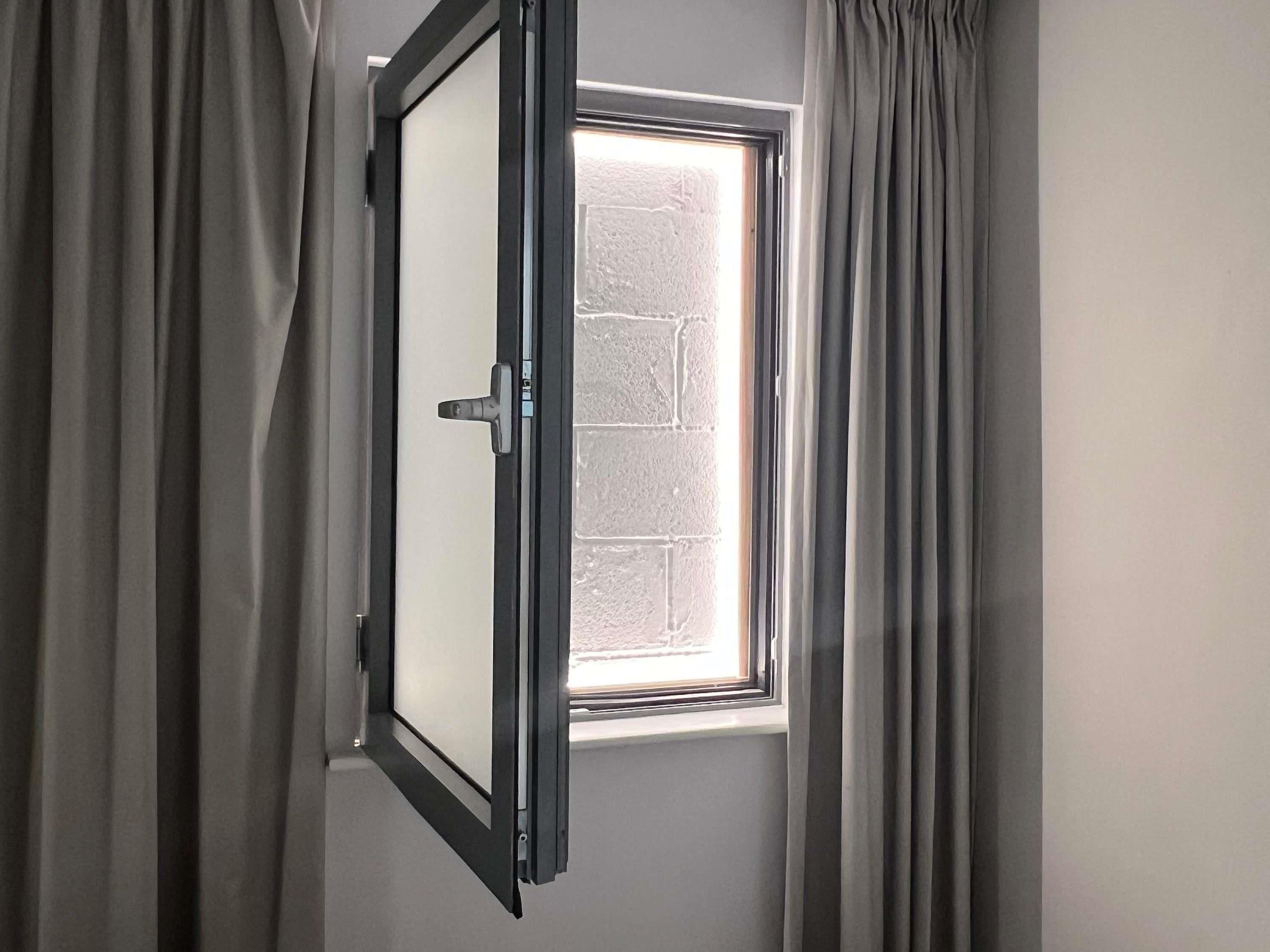 Une pièce avec une fenêtre, des rideaux et une porte.