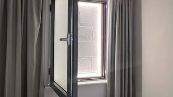 Une pièce avec une fenêtre, des rideaux et une porte.