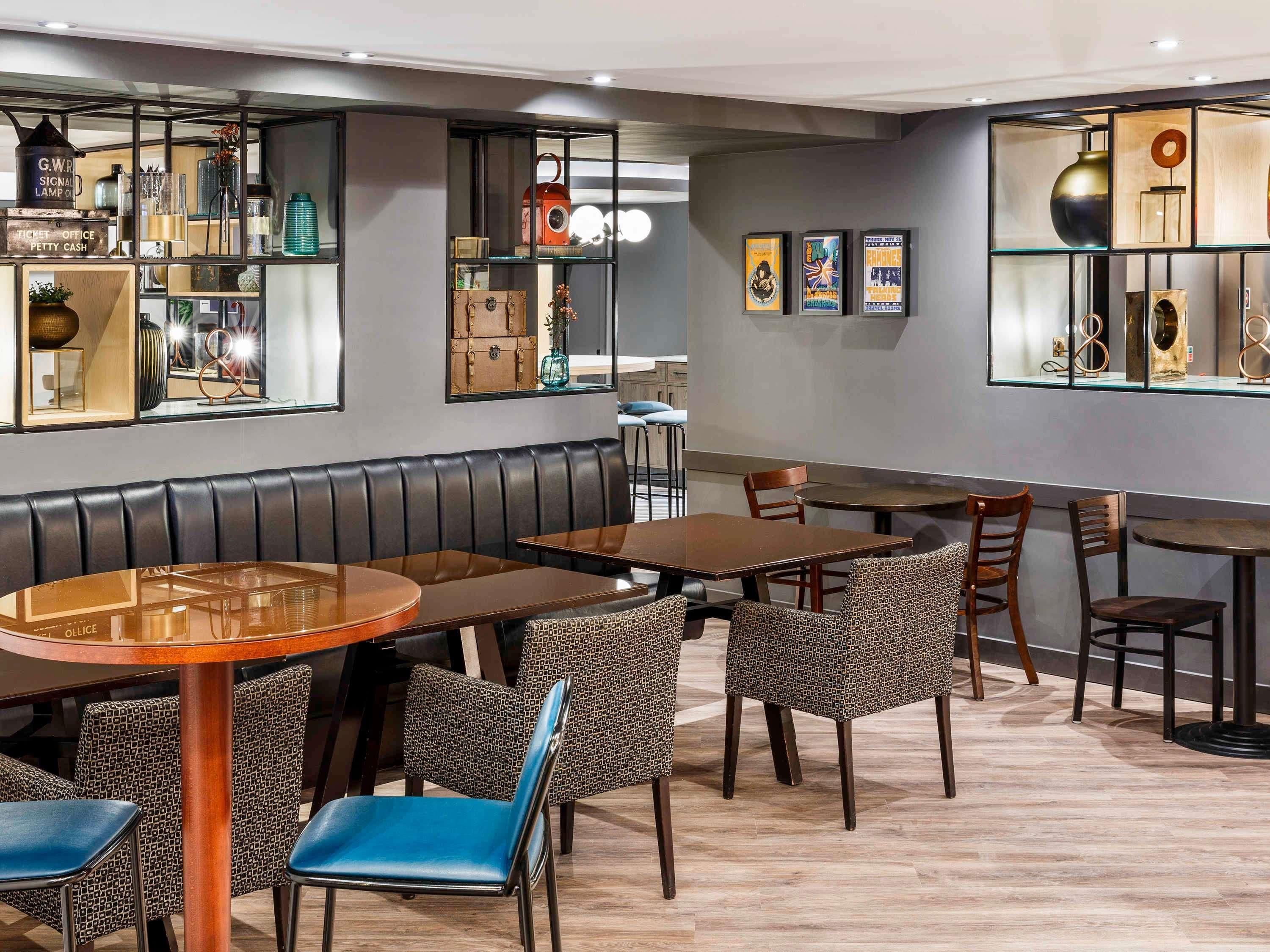 A restaurant with booths, tables, and chairs. There are shelves with various items and framed pictures on the walls.