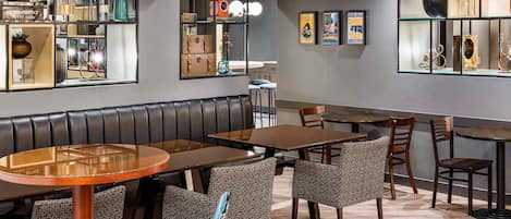 Un restaurant avec des banquettes, des tables et des chaises. On y trouve des étagères remplies de divers objets et des tableaux encadrés accrochés aux murs.