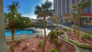 A hotel with a swimming pool surrounded by palm trees and red mulch landscaping. - 110 South Hampton - Barefoot Resort Rentals (Myrtle Beach)