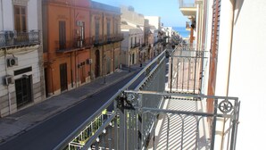 A narrow street with buildings on both sides, a metal railing, and a clear sky. - Exclusive Home (Castellammare del Golfo)