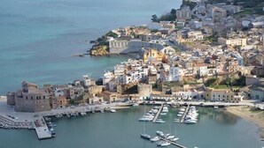 A coastal town with a marina filled with boats, historic buildings, and a prominent church. - Exclusive Home (Castellammare del Golfo)