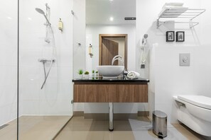 A modern bathroom with a glass shower enclosure, a wooden vanity, a white sink, and a toilet. - P&O Apartments Oxygen Wronia 3 (Warsaw)