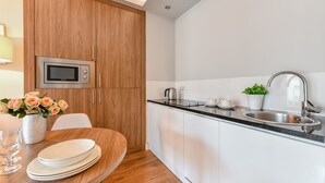Una cocina moderna con armarios de madera, un microondas de acero inoxidable y un lavamanos con grifo.