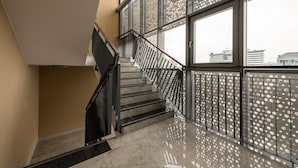 Una escalera moderna con barandillas de metal y ventanas amplias.