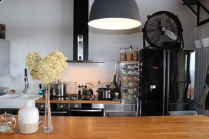 A modern kitchen with stainless steel appliances, a wooden dining table, and a decorative vase with dried flowers.