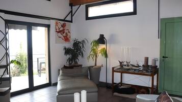 Una sala de estar con un sofá, dos plantas en macetas, una mesa con objetos decorativos y una puerta verde.