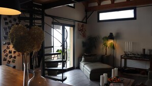 A modern living room with a wooden dining table, a sofa, and a staircase. - Skylark Bed & Breakfast (Grasse)
