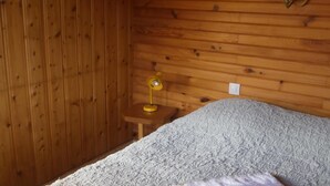 Una habitación con paneles de madera, una cama, una mesita de noche y una lámpara.