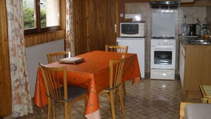 Una cocina compacta con una mesa de comedor, sillas, microondas, estufa y refrigerador.