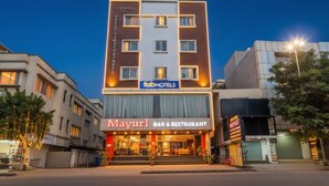 Un edificio de varios pisos con un letrero de 'fab hotels', un bar y restaurante 'Mayuri', y un letrero de 'The Garden'.