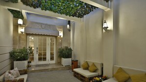 Un'area patio esterna con posti a sedere, piante in vaso e una porta che dà su un ambiente interno.