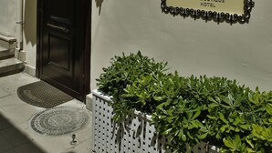 Entrada de un hotel boutique con una puerta oscura, un toldo color beige y un letrero que dice 'Sweet House Boutique Hotel'.