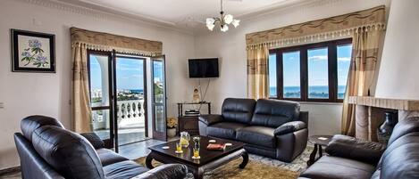 A living room with leather sofas, a coffee table, and a TV on the wall.