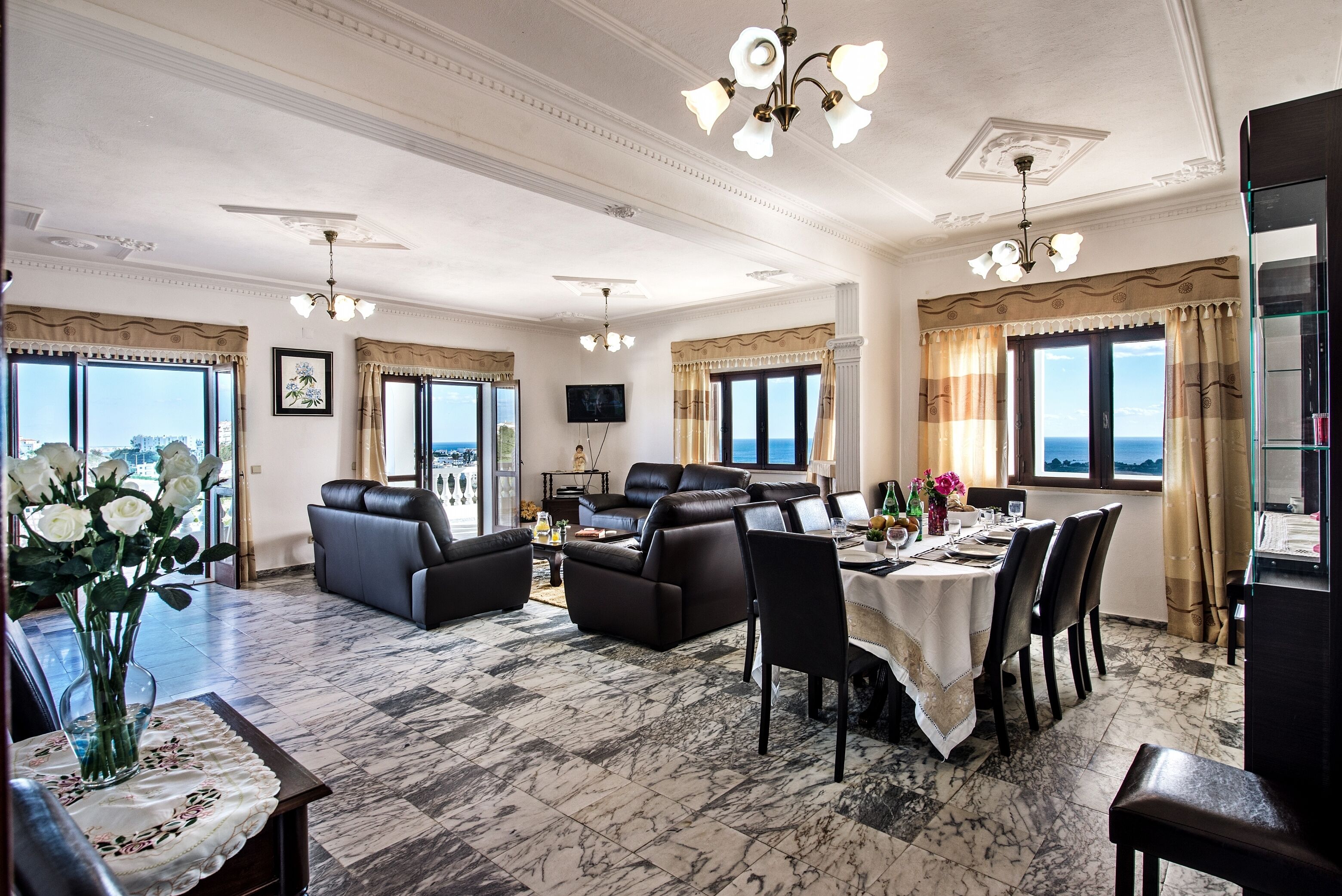Een ruime woonkamer met een open haard, een eethoek met een tafel voor vier personen, en grote ramen met uitzicht op de stad.